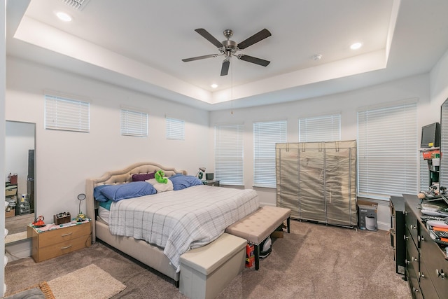 bedroom with light carpet, ceiling fan, and a tray ceiling