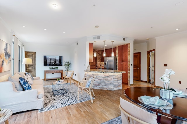 living room featuring crown molding and light hardwood / wood-style flooring