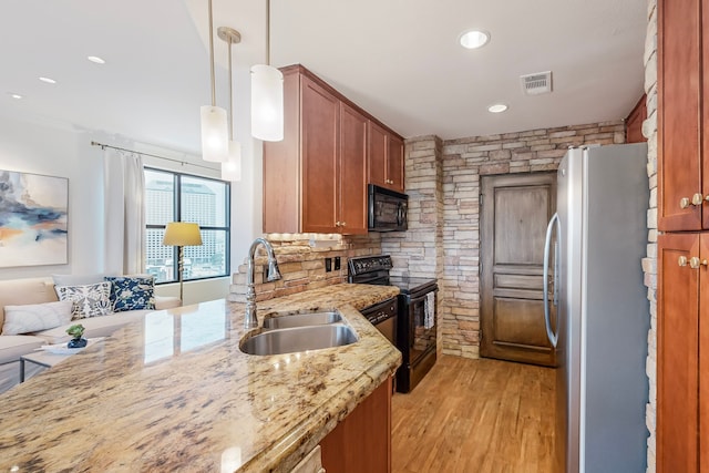 kitchen with sink, light stone countertops, black appliances, decorative light fixtures, and light wood-type flooring