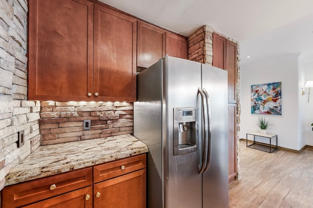 kitchen featuring stainless steel fridge with ice dispenser, decorative backsplash, light hardwood / wood-style flooring, and light stone countertops