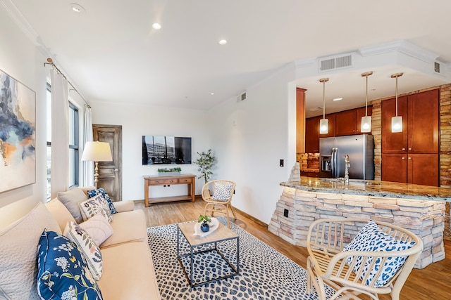 living room featuring sink, ornamental molding, and light wood-type flooring