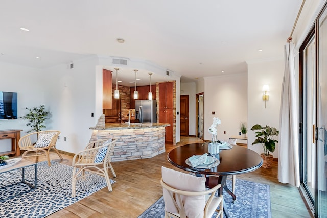 dining area featuring ornamental molding, sink, light hardwood / wood-style flooring, and a baseboard heating unit