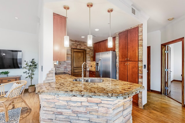 kitchen with sink, stainless steel fridge, kitchen peninsula, pendant lighting, and light hardwood / wood-style floors