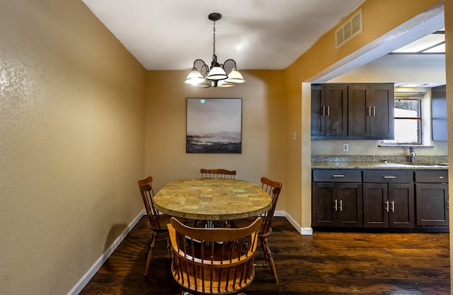 dining area with sink, dark hardwood / wood-style floors, and a chandelier