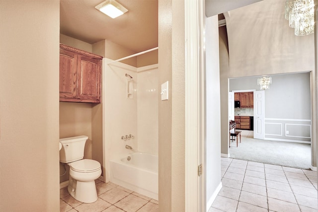 bathroom with an inviting chandelier, washtub / shower combination, toilet, and tile patterned flooring