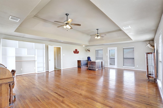 living room with hardwood / wood-style floors, ceiling fan, and a tray ceiling