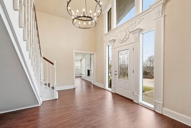 foyer entrance with dark hardwood / wood-style floors, an inviting chandelier, and a towering ceiling