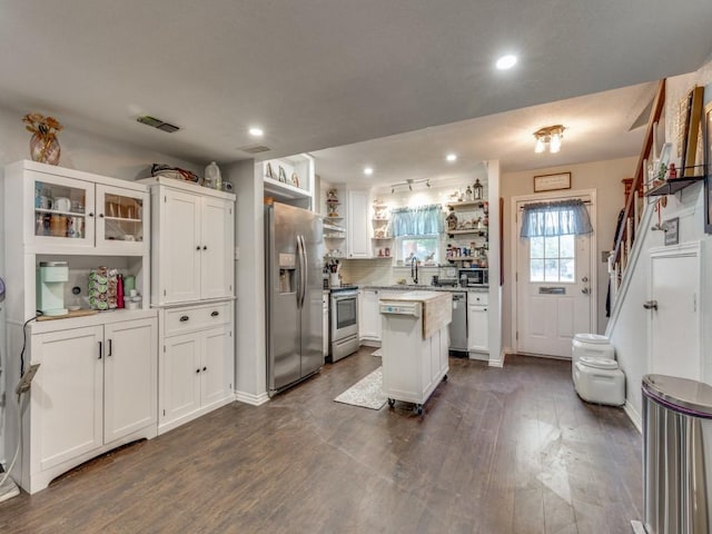 kitchen with white cabinetry, dark wood-type flooring, stainless steel appliances, and a center island