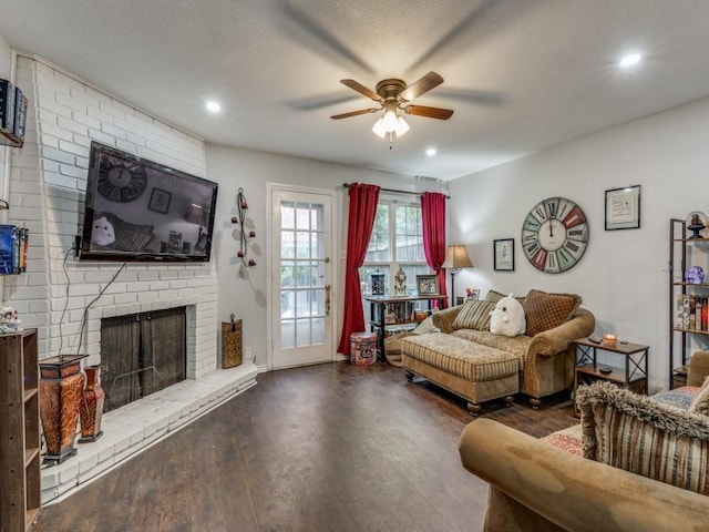 living room featuring ceiling fan, dark wood-type flooring, a textured ceiling, and a fireplace