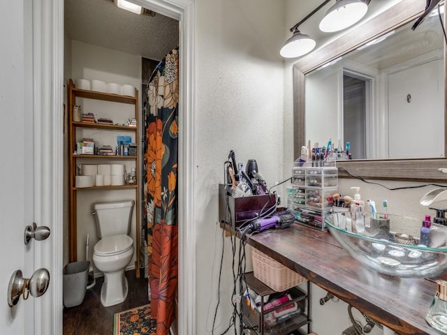 bathroom featuring sink, wood-type flooring, a textured ceiling, a shower with curtain, and toilet