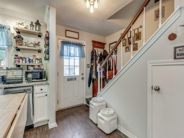 interior space with butcher block countertops, appliances with stainless steel finishes, white cabinetry, backsplash, and dark hardwood / wood-style floors