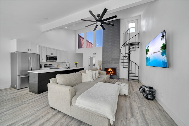 living room with light hardwood / wood-style flooring, sink, a fireplace, and ceiling fan