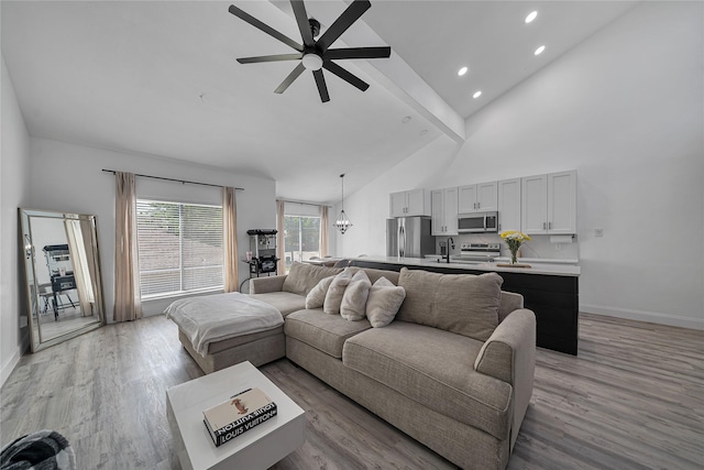 living room featuring high vaulted ceiling, beamed ceiling, sink, ceiling fan, and light hardwood / wood-style floors