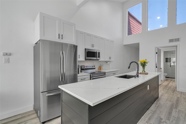 kitchen with light stone countertops, sink, stainless steel appliances, and a center island