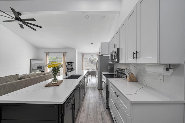 kitchen with light stone counters, sink, an island with sink, and appliances with stainless steel finishes