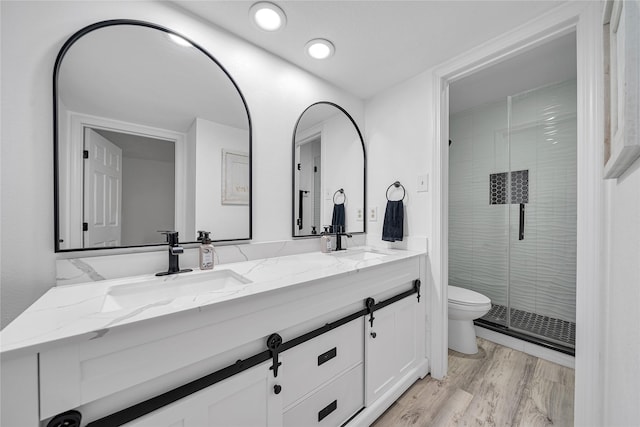 bathroom with hardwood / wood-style flooring, vanity, toilet, and a shower with shower door