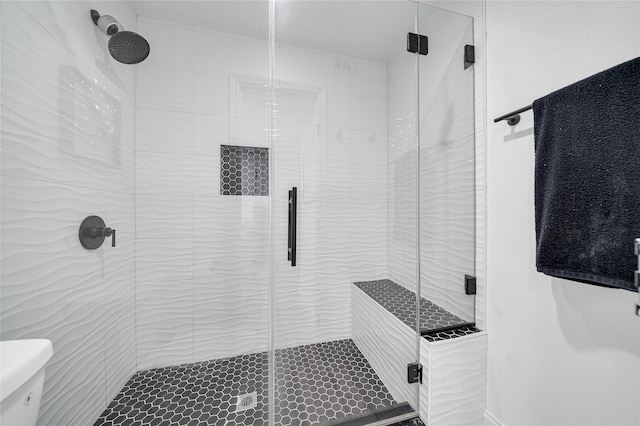 bathroom featuring toilet and a shower with shower door