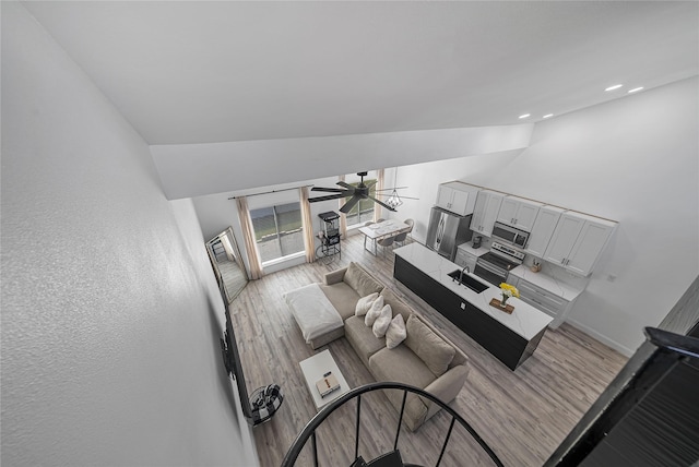 living room featuring vaulted ceiling, sink, ceiling fan, and light wood-type flooring