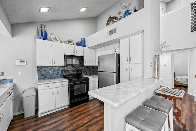 kitchen featuring a breakfast bar area, black appliances, kitchen peninsula, and white cabinets