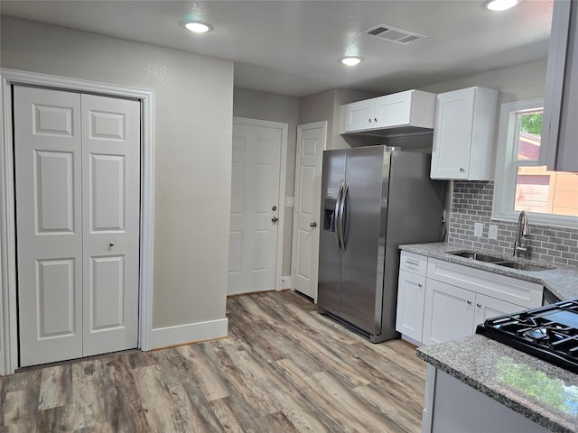 kitchen featuring white cabinetry, sink, stainless steel fridge, and light stone countertops