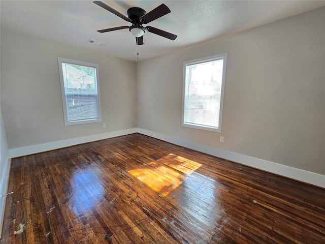 spare room with ceiling fan, a healthy amount of sunlight, and dark hardwood / wood-style flooring