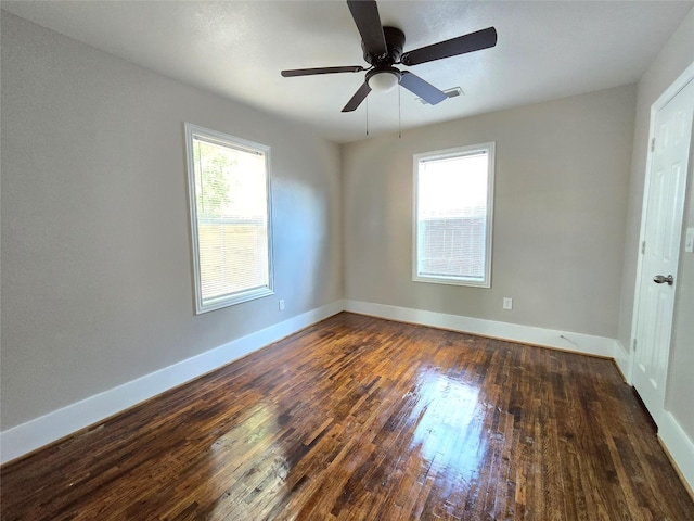 empty room featuring ceiling fan, a healthy amount of sunlight, and dark hardwood / wood-style floors