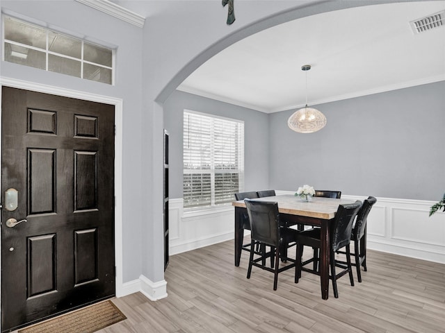 foyer entrance with ornamental molding, a chandelier, and light wood-type flooring