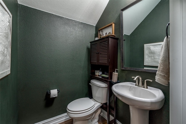 bathroom featuring hardwood / wood-style flooring, lofted ceiling, toilet, and a textured ceiling