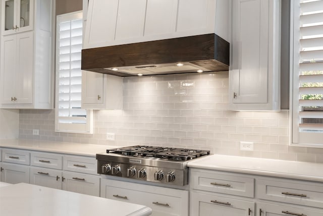 kitchen featuring tasteful backsplash, light countertops, stainless steel gas stovetop, glass insert cabinets, and white cabinets