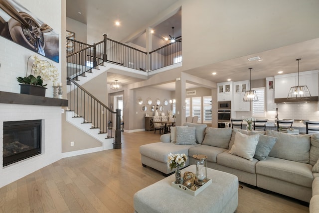 living area with visible vents, baseboards, stairs, light wood-type flooring, and a fireplace