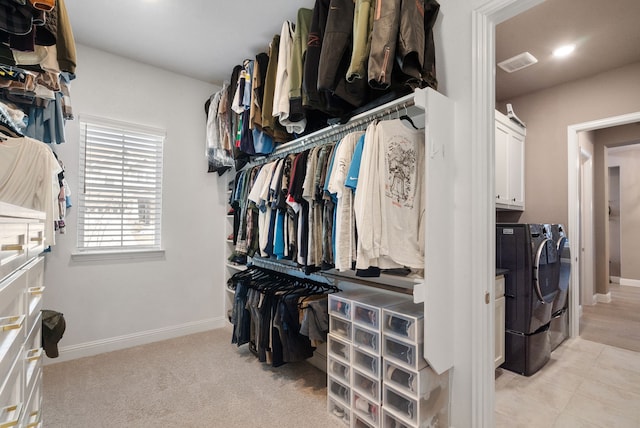 spacious closet featuring washer and clothes dryer, visible vents, and light colored carpet