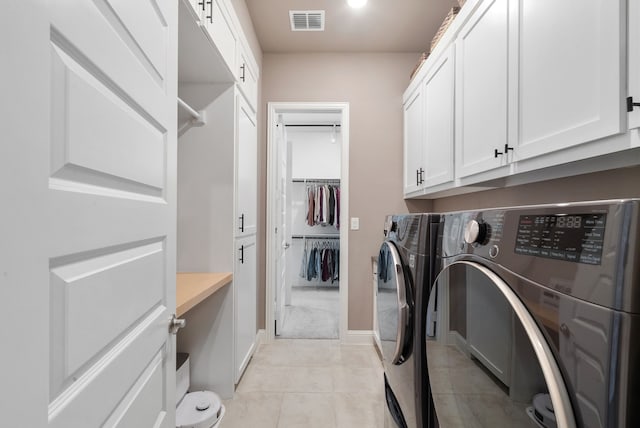 washroom with light tile patterned floors, visible vents, baseboards, cabinet space, and washer and clothes dryer