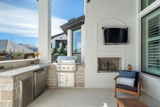 view of patio featuring an outdoor brick fireplace, an outdoor kitchen, and grilling area