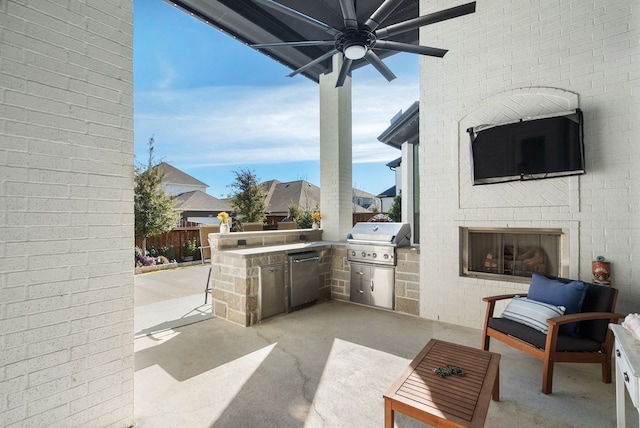 view of patio / terrace featuring an outdoor brick fireplace, a grill, an outdoor kitchen, and fence