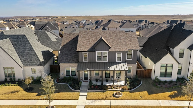 view of front of house with a standing seam roof, a residential view, fence, and a front lawn