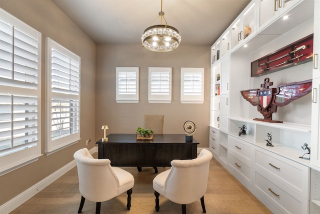 office area featuring baseboards, light wood finished floors, and an inviting chandelier