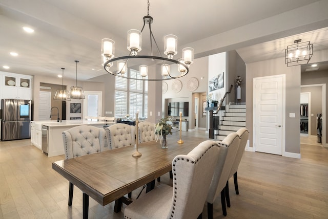 dining area with stairs, light wood-style floors, recessed lighting, and an inviting chandelier