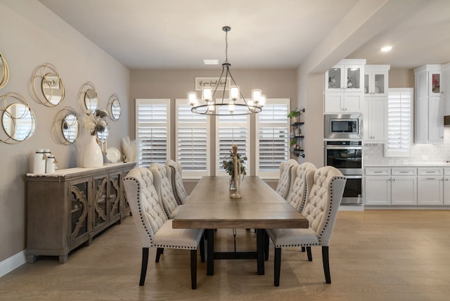 dining space featuring a chandelier, baseboards, and light wood finished floors