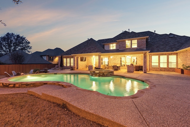 pool at dusk featuring a patio and an in ground hot tub