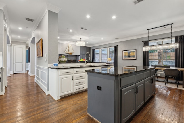 kitchen featuring sink, ornamental molding, dark hardwood / wood-style floors, a kitchen island, and white cabinets