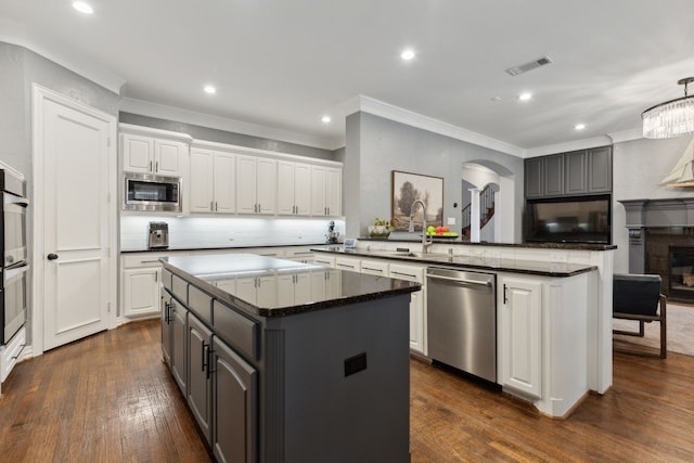 kitchen featuring a kitchen island, white cabinetry, sink, kitchen peninsula, and stainless steel appliances