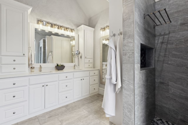 bathroom with vanity, lofted ceiling, and a tile shower