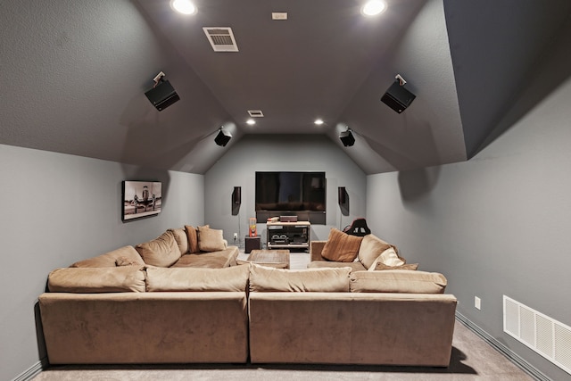 carpeted cinema room with vaulted ceiling