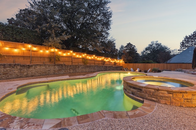 pool at dusk with an in ground hot tub