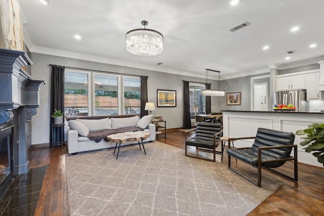 living room with crown molding, a chandelier, and light wood-type flooring