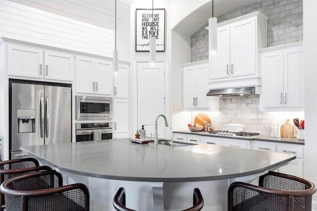 kitchen with appliances with stainless steel finishes, a breakfast bar area, a sink, and decorative backsplash