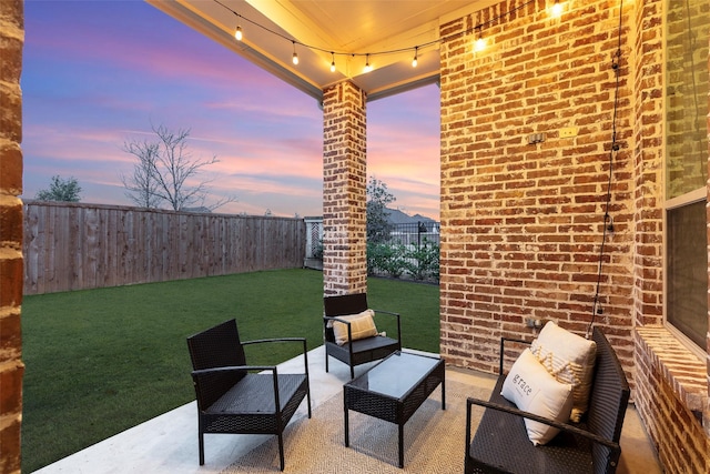 patio terrace at dusk with an outdoor living space and a yard