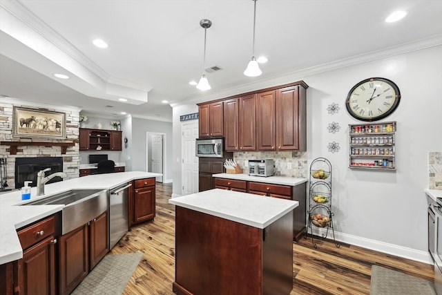 kitchen with sink, hardwood / wood-style flooring, appliances with stainless steel finishes, a center island, and decorative light fixtures