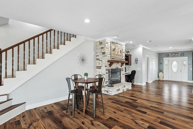 dining area featuring dark wood-type flooring, ornamental molding, and a fireplace