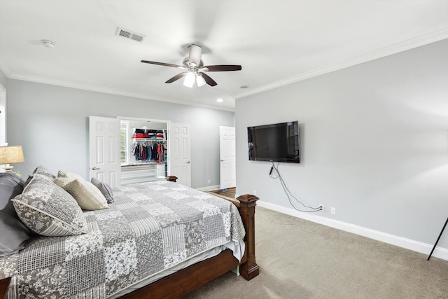 carpeted bedroom featuring ceiling fan, ornamental molding, a closet, and a walk in closet